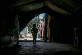Unrecognizable child walking in tent. Photo by Ahmed akacha.