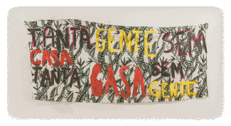 A graphic with green feather patterns on a beige background, text on it in Portuguese says “Tanta Gente sem casa. tanta casa sem gente” which means "So many people without a home, so many homes without people"