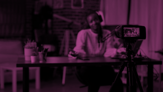 Blurred woman in the background looking at a camera in front of her